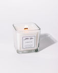 A white candle named 'Amelia' in a clear glass holder with a label in front.