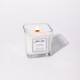 A white candle with a label that reads 'NADOR', placed in a clear glass holder.