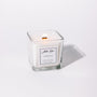 A white candle named 'Amelia' in a clear glass holder with a label in front.